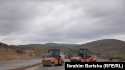 Dy makina pune të stacionuara në një segment të shtruar të rrugës.