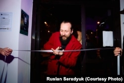 Джоні Косьмік пераразае стужку на адкрыцьці ўласнай выставы. Фота Руслана Серадзюка