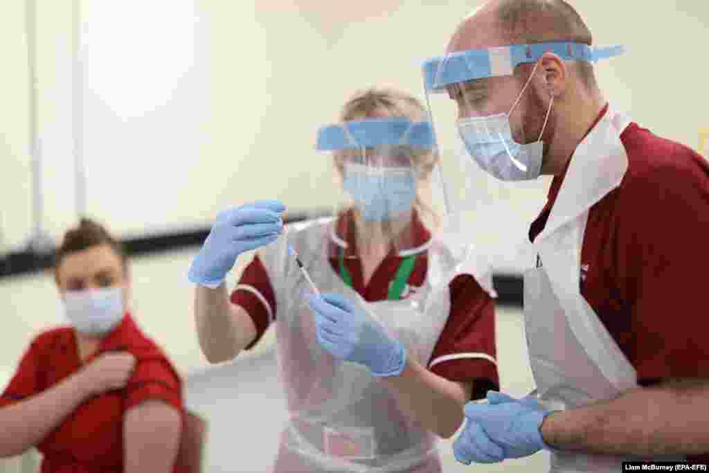 Медична сестра наповнює шприц вакциною від Covid-19 перед тим, як зробити ін&#39;єкцію сестрі Джоанні Слоун (ліворуч), першій людині в Північній Ірландії, яка отримала першу з двох вакцинних введень Pfizer/BioNTech Covid-19 у госпіталі Королеви Вікторії в Белфасті Північна Ірландія, Велика Британія, 8 грудня 2020 року