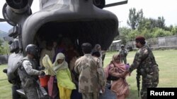 U.S. and Pakistani service members help flood victims exit a U.S. Army helicopter in Khwazakhela 