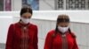 Women wearing protective face masks walk along the street in Ashgabat.