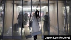 მგზავრები დამცავი ნიღბებით პეკინის რკინიგზის სადგურში