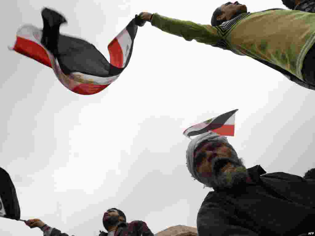 Anti-government protesters shout slogans and wave the national flag at a barricade in Cairo's Tahrir Square.