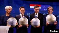 Представители стран ЕС позируют с моделью монеты евро после церемонии подписания документа о переходе Хорватии на евро в Брюсселе. Бельгия, 12 июля 2022 года