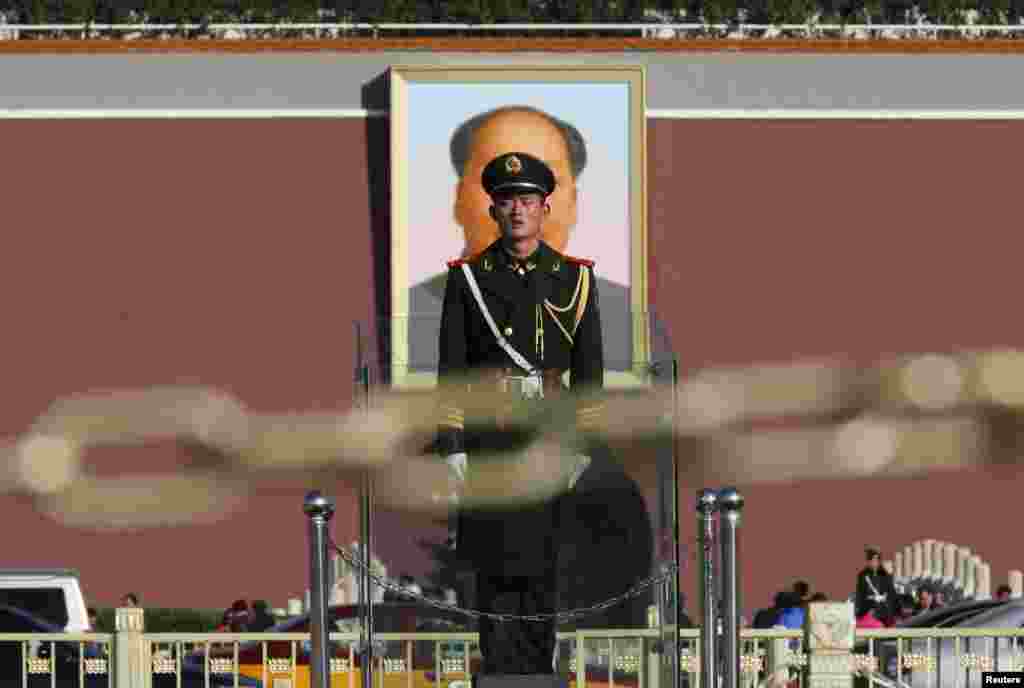 Часовой на фоне портрета Мао, расположенного на &quot;Воротах небесного спокойствия&quot; на площади Тяньаньмэнь - именно здесь была провозглашено создание КНР. Каждые несколько лет износившийся от воздействия окружающей среды портрет меняют на новый.