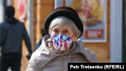 Женщина в защитной маске идет по улице Алматы. Иллюстративное фото
