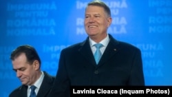 Romanian President Klaus Iohannis (right) and Prime Minister Ludovic Orban greet supporters after announcing the results of the presidential election in Bucharest on November 24. 
