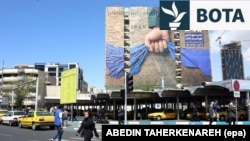 Iranianë duke kaluar pranë një bilbordi në Teheran për Ngushticën e Hormuzit ku shkruhet "Gjithmonë në duart e Iranit". 15 prill 2026. 