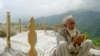 Eighty-year-old Gul Shirin prays next to the fresh graves of 13 family members who died in flooding in Swat Valley in August.