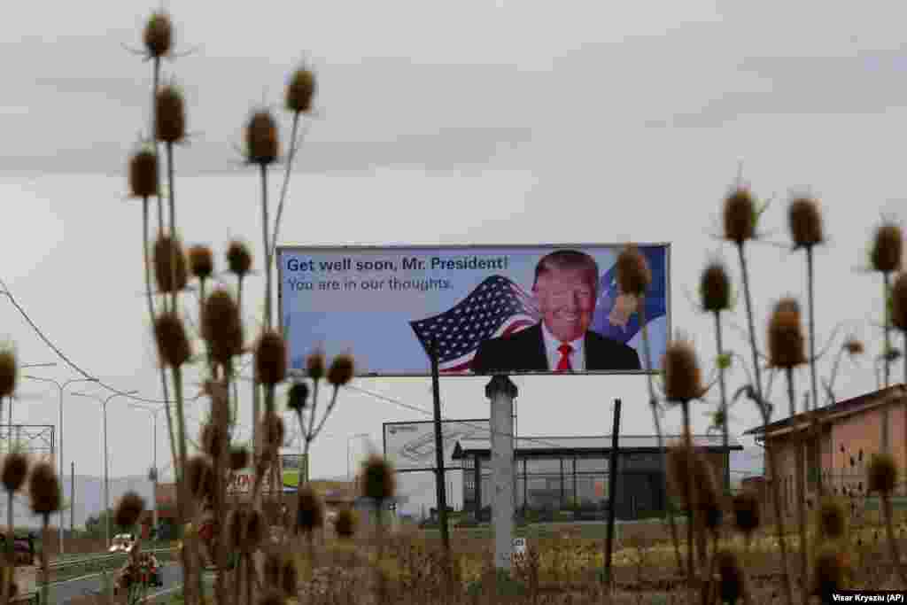 Veliki bilbord u kojem se predsedniku Sjedinjenih Američkih Država Donaldu Trampu želi brz oporavak od bolesti koju izaziva korona virus postavljen je u selu Slatina, zapadno od glavnog grada Kosova, Prištine (AP/Visar Kryeziu)