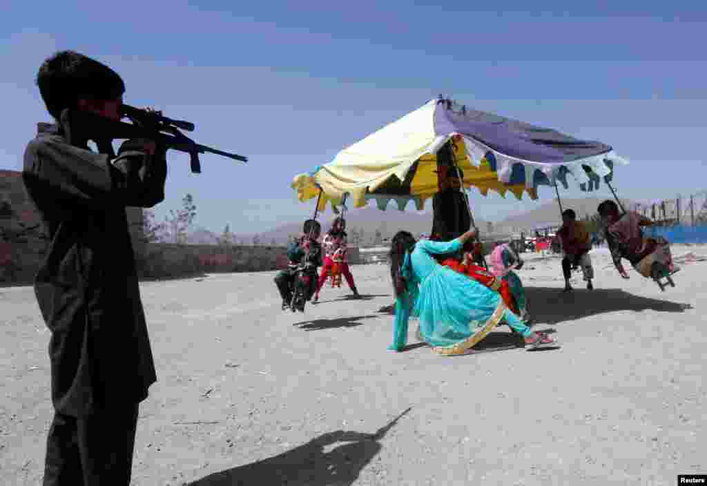 An Afghan boy looks through the scope of a toy gun as other children ride on swings during the first day of the Muslim holiday of Eid al-Fitr, which marks the end of the holy month of Ramadan, in Kabul, on June 25. (Reuters/Omar Sobhani)