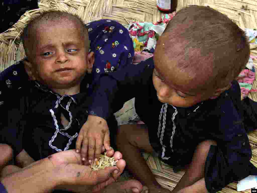 A woman displaced from floods feeds her children at a temporary shelter in Sukkur, Sindh Province, Pakistan on August 20. The United Nations warned on August 16, that up to 3.5 million children were at risk from water-borne diseases in flood-hit Pakistan and that it was bracing to deal with thousands of potential cholera cases. Photo by Rehan Khan for epa