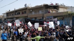 Antigovernment protesters, some holding signs reading "We only love freedom," march in the northeastern Syrian town of Qamishli on April 1.