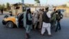 Afghan security officials stop people at a checkpoint in Kandahar on June 8.