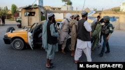 Afghan security officials stop people at a checkpoint in Kandahar on June 8.