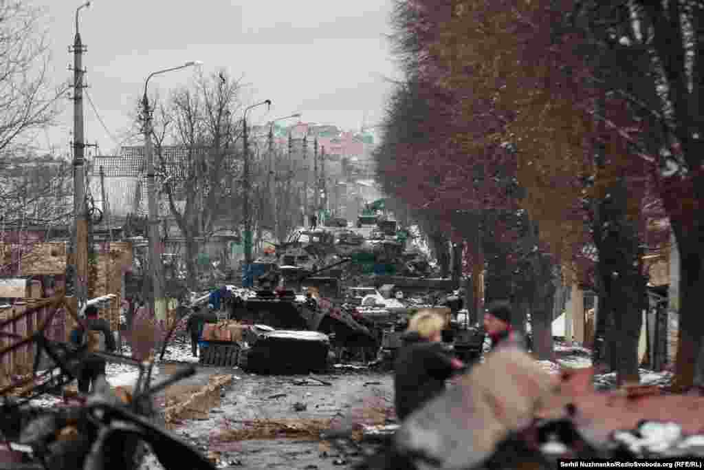 Місцеві жителі розглядають колону знищеної російської техніки на вулиці Вокзальна в Бучі, Київщина, 1 березня 2022 року. Через декілька днів російські війська окупують місто