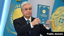 Президент Касым-Жомарт Токаев держит Конституцию Казахстана