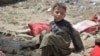 په خوست کې یو ماشوم په ورښتونو کې له خپل زیانمن شوي کور سره نېږدې ناست دی - د اګست شپږمې انځور.