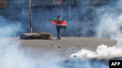 Un protestatar cu drapelul național kenyan în timpul intervenței poliției din 25 iunie, într-o suburbie a orașului Nairobi.