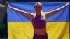 Viktoriya Tkachuk of Ukraine poses for a teammate with a flag signed by the Ukrainian rock band The Hardkiss as she trains before the World Athletics Championships in Eugene, Oregon, on July 14.