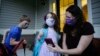 U.S. -- Virus Outbreak Schools // Rachel Adamus, right, shows her children, Paul, left, and Neva, 5, center, an app on her phone showing when the school bus will arrive near their home, on Monday, Aug. 3, 2020, in Dallas,