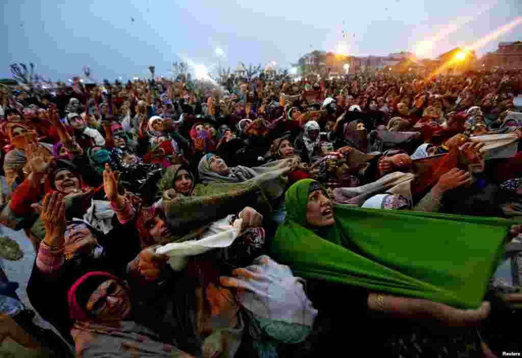 Kashmiri Muslim women raise their arms as they pray upon seeing a relic of the Prophet Muhammad being displayed during the festival of Eid-e-Milad-ul-Nabi at Hazratbal shrine on a cold winter morning in Srinagar on December 24. (Reuters/Danish Ismail&nbsp;)