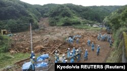 Сотрудники полиции разыскивают пропавших людей на месте оползня, вызванного сильным дождем в городе Цунаги, префектура Кумамото, на юге Японии