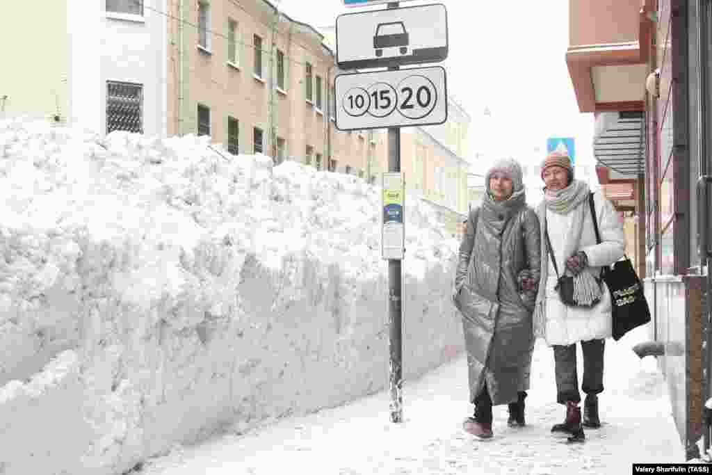 Женщины проходят мимо сугробов на Большой Никитской улице в центре Москвы