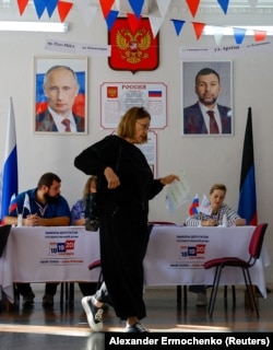 Голосування в окупованому Донецьку, 20 вересня 2026 року. На стіні – портрети Путіна та очільника місцевої окупаційної адміністрації Дениса Пушиліна, а також інфоплакат з гімном, прапором та гербом РФ. Над ними окремо – герб РФ