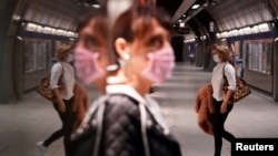 Dy gra mbajnë maska mbrojtëse kundër koronavirusit në një stacion metroje. 