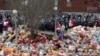 People stand near toys, flowers, balloons, and other items as they gather to commemorate the victims of a shopping mall fire on the day of national mourning in Kemerovo on March 28.