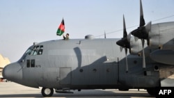 A member of the Afghan Air Force raises the national flag on top of a C-130 transport aircraft at Kabul's international airport on October 9, 2013.