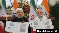 Indian Prime Minister Narendra Modi, right, with Iranian President Hassan Rouhani release a postal stamp commemorating growing economic and trade ties between the two nations in New Delhi, February 17, 2018