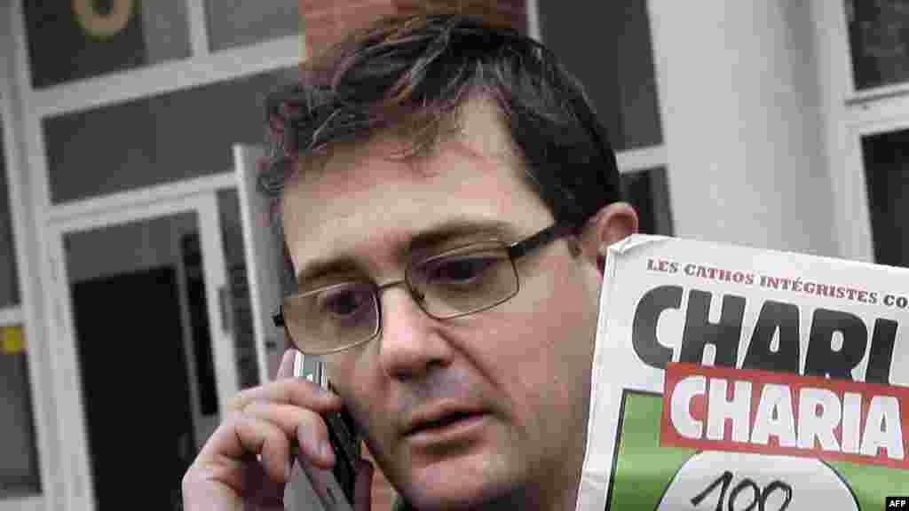 Charlie Hebdo&#39;s publisher, known only as Charb, uses his cell phone as he shows a special edition of the magazine in Paris on November 2, 2011.