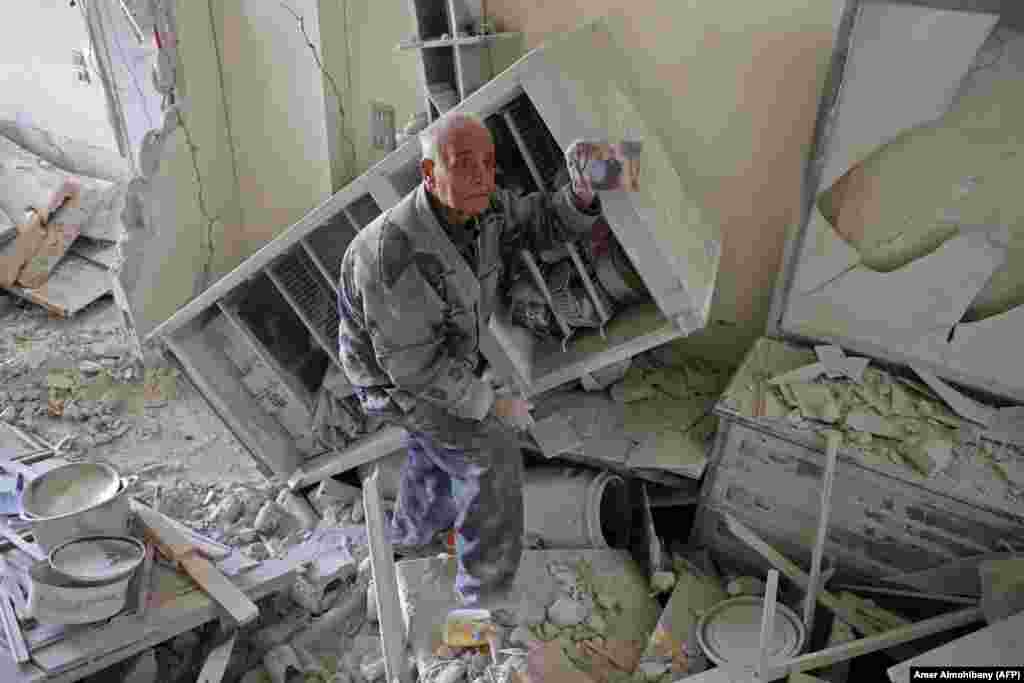 An elderly Syrian man shows a family picture after he recovered it from the rubble of his house in Kafar Batna in the Syrian rebel enclave of eastern Ghouta following reported air strikes by Syrian government forces. (AFP/Amer Almohibany)