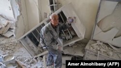 SYRIA -- An elderly Syrian man shows a family picture after he recovered it from the rubble of his house in Kafar Batna in the Syrian rebel enclave of Eastern Ghouta on March 1, 2018 following reported air strikes by Syrian government forces. 