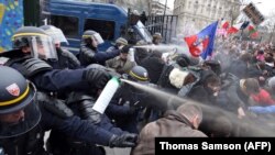 Riot police spray tear gas on demonstrators during clashes on the Champs-Elysees.