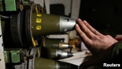 Український військовий показує 155-міліметрові снаряди всередині самохідної гаубиці поблизу Бахмута, фото ілюстративне