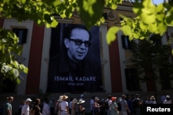 Njerëzit kalojnë pranë një fotografie të shkrimtarit Ismail Kadare, gjatë homazheve në Tiranë më 3 korrik 2024.