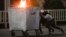 KYRGYZSTAN -- Protesters push a burning trash can towards riot police during a rally against the results of a parliamentary vote in Bishkek, October 5, 2020