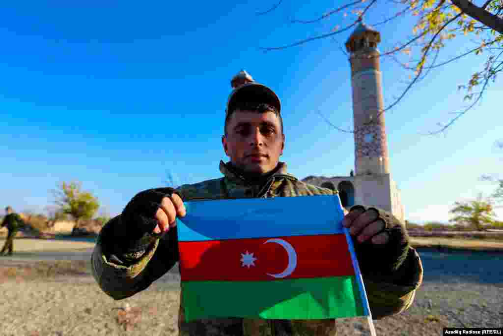 An Azerbaijani poses with his country&#39;s flag in front of Agdam mosque on November 24.