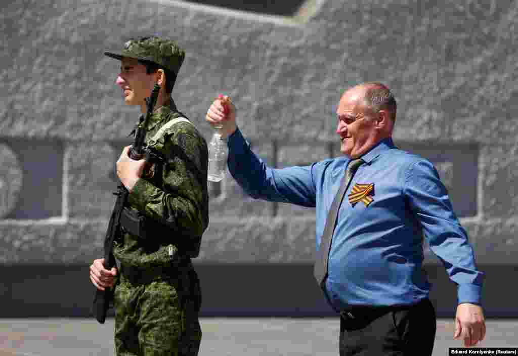 A participant sprays water on an honor guard to cool him off before the ceremony at a World War II memorial in Stavropol, Russia. (Reuters/Eduard Korniyenko)