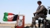 Afghan security officials patrol a highway in Helmand on June 14.