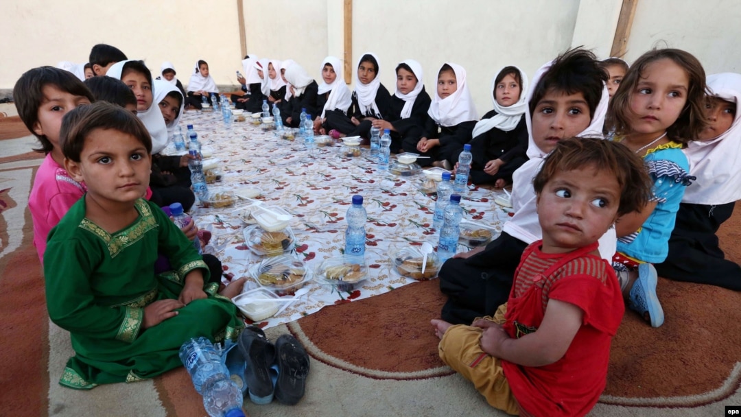 A group of young Afghans wait to eat iftar, the meal traditionally taken after sunset prayers to break the fast during the Islamic holy fasting month of Ramadan, in Herat.