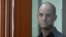 U.S. journalist Evan Gershkovich looks out from inside a glass defendants' cage prior to a hearing at a Russian court in Yekaterinburg on June 26.