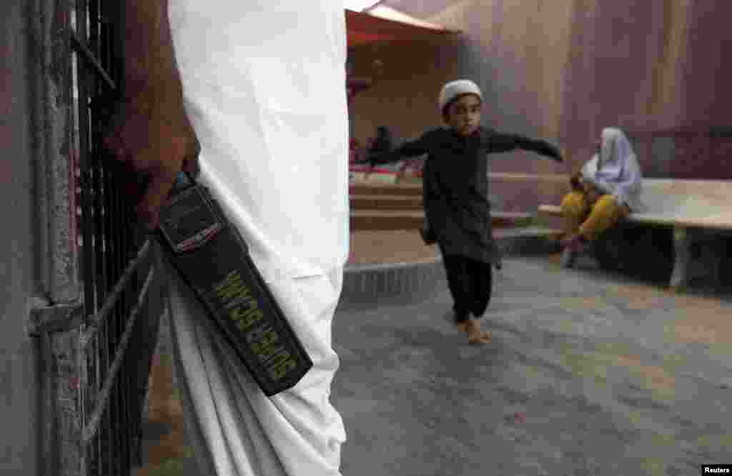 A security guard with a metal detector stands at the entrance to the shrine of Hasan-al-Maroof Sultan Manghopir, better known as the crocodile shrine, on the outskirts of Karachi. (Reuters/​Akhtar Soomro)