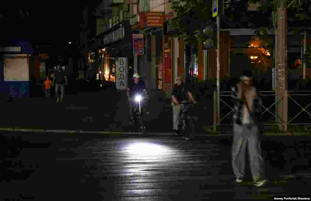 Cyclists and pedestrians on a darkened street in Yevpatoria on July 5.The electricity crisis in Crimea, which comes amid ongoing fuel shortages throughout the peninsula, has led to critical services, such as water supplies, being affected in some cities, and tram services suspended.
