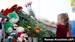Девочка возлагает цветы у школы в Казани