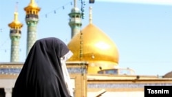 A veiled woman is seen in Qom, with golden-domed mosque in the background. File photo