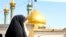 A veiled woman is seen in Qom, with golden-domed mosque in the background. File photo